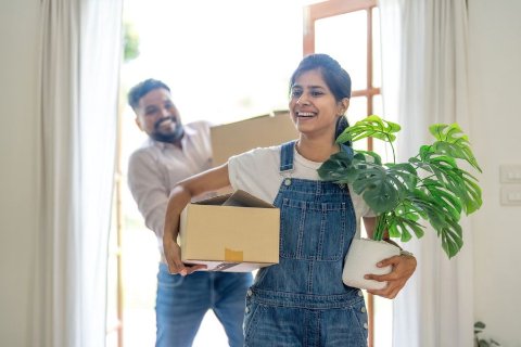 Couple portant des cartons et des plantes dans leur nouveau logement le jour du déménagement
